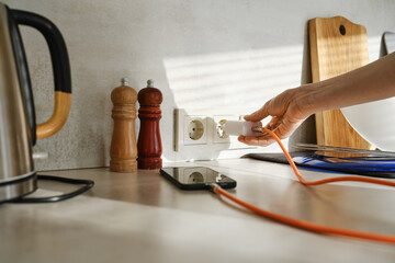 Main branchant un chargeur sur prise électrique de cuisine, diagnostic électricité