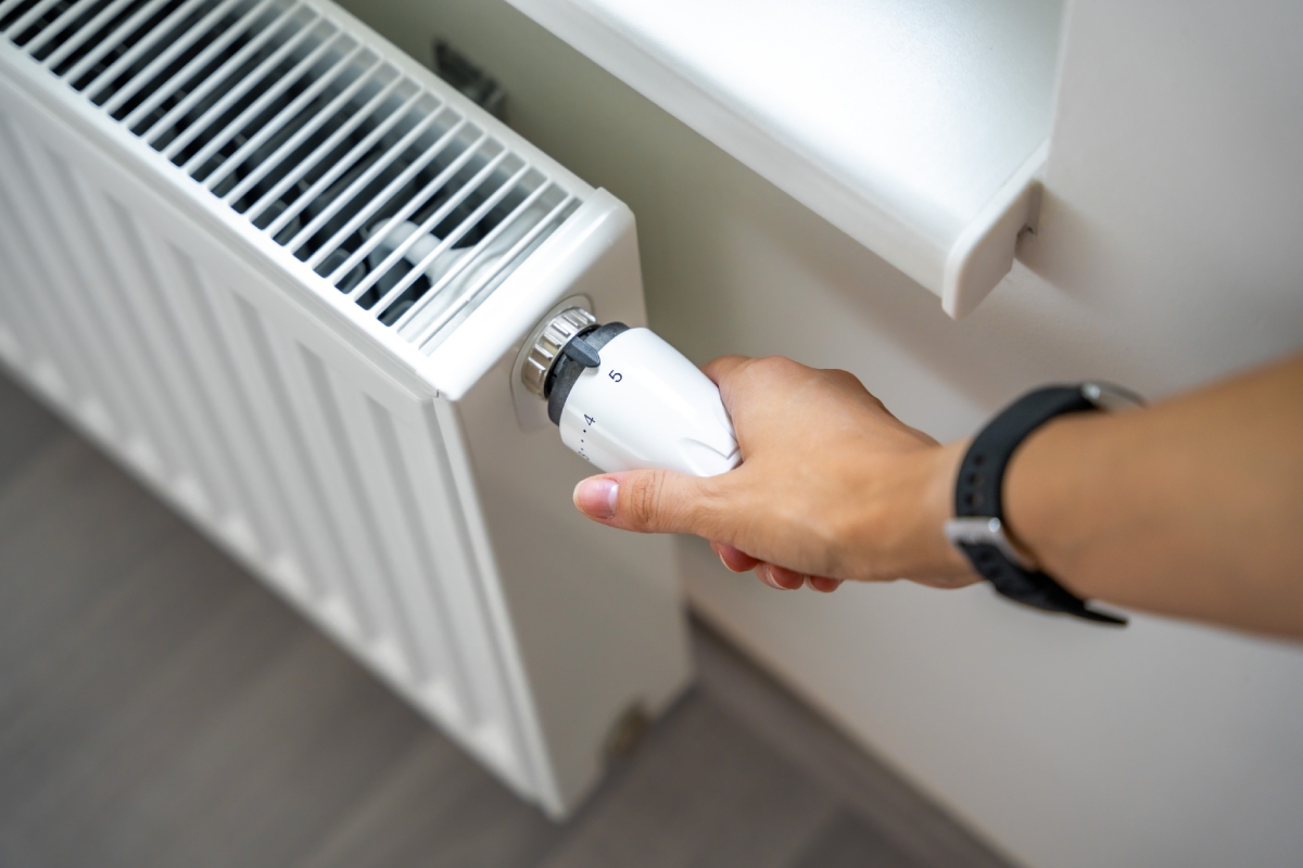 Main réglant un robinet thermostatique sur radiateur, diagnostic gaz
